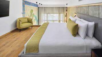 Una habitación de hotel moderna con una cama grande, un sofá, un televisor y un mural en la pared.