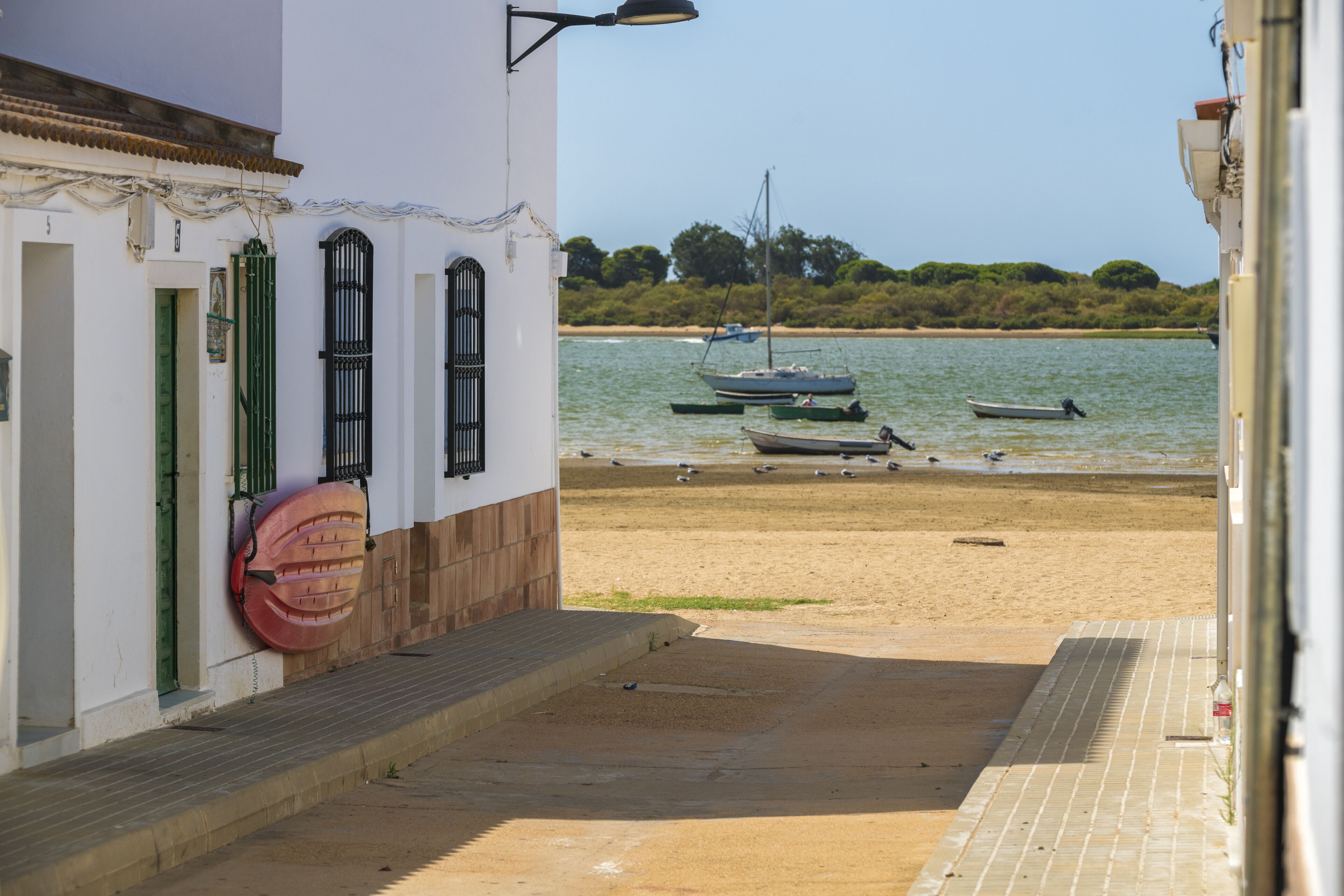 A coastal building with a paved walkway leading to a sandy beach.