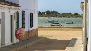 A coastal building with a paved walkway leading to a sandy beach.