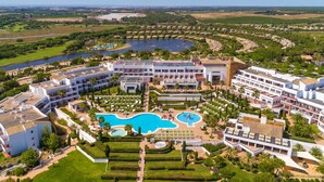 A resort with multiple buildings, a large central pool, and a lake in the background. - Hotel Fuerte El Rompido (Cartaya)