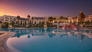 A hotel pool area with a clear view of the pool, lounge chairs, and palm trees.