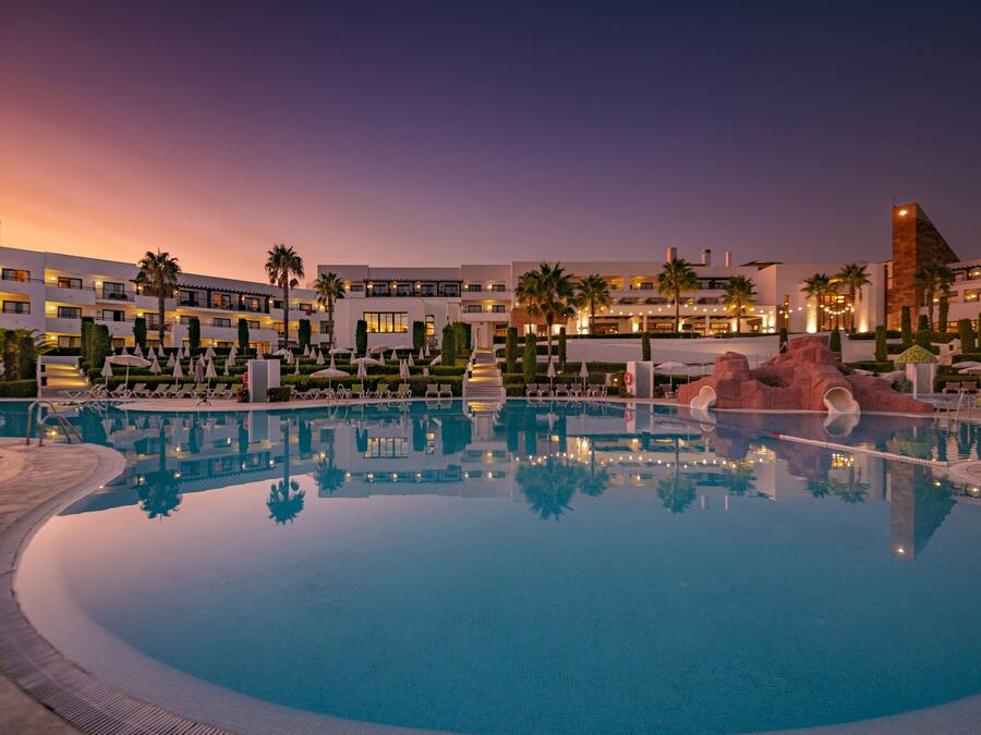 A hotel pool area with a clear view of the pool, lounge chairs, and palm trees.
