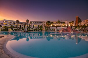 Una piscina cubierta, una piscina al aire libre, sombrillas, tumbonas