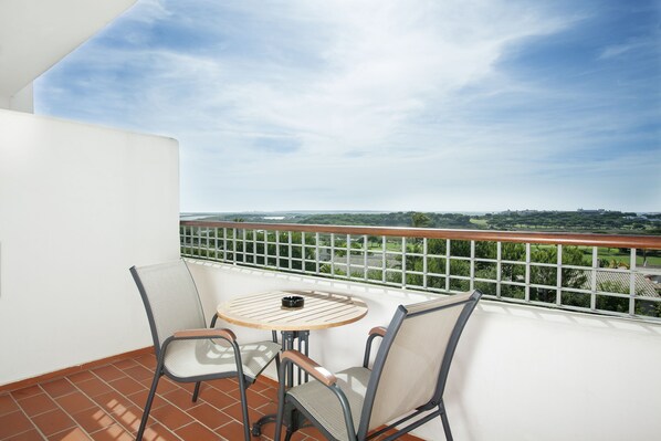 A balcony with a table and chairs, a view of the landscape, and a railing.