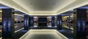 Een moderne spa met een centraal waterkunstwerk, zitgedeeltes en een receptiebalie.