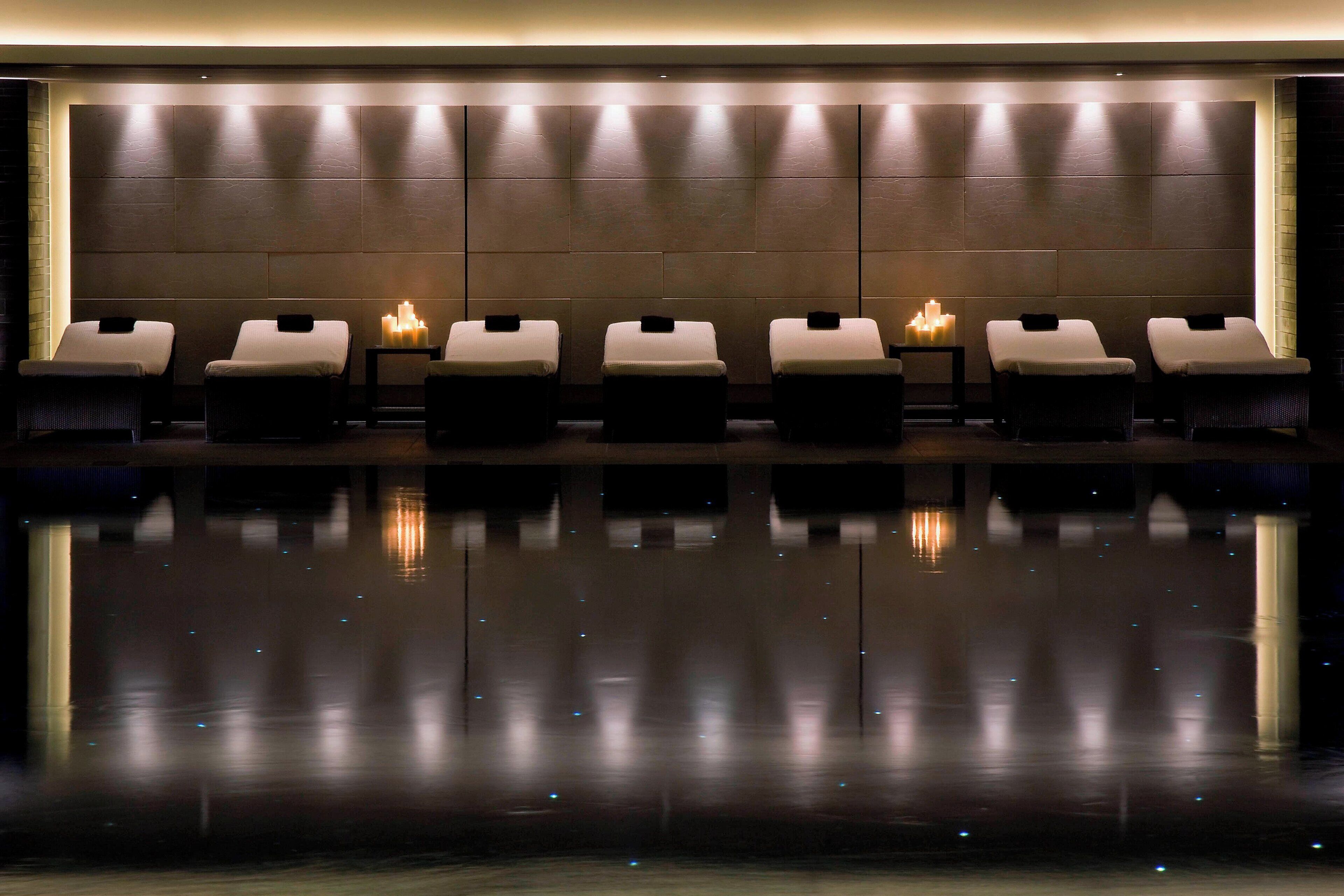 A spa area with six massage chairs aligned against a wall, each with a small table and candle.