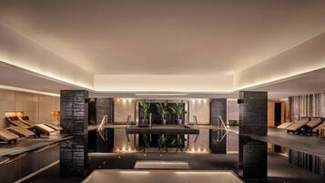 A modern spa area with a central water feature, seating areas, and a large wall with a vertical garden.
