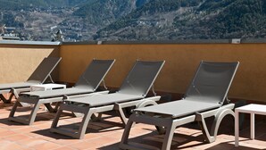 A terrace with sun loungers and a table, overlooking a mountainous landscape. - Hotel Best Andorra Center (Andorra la Vella)