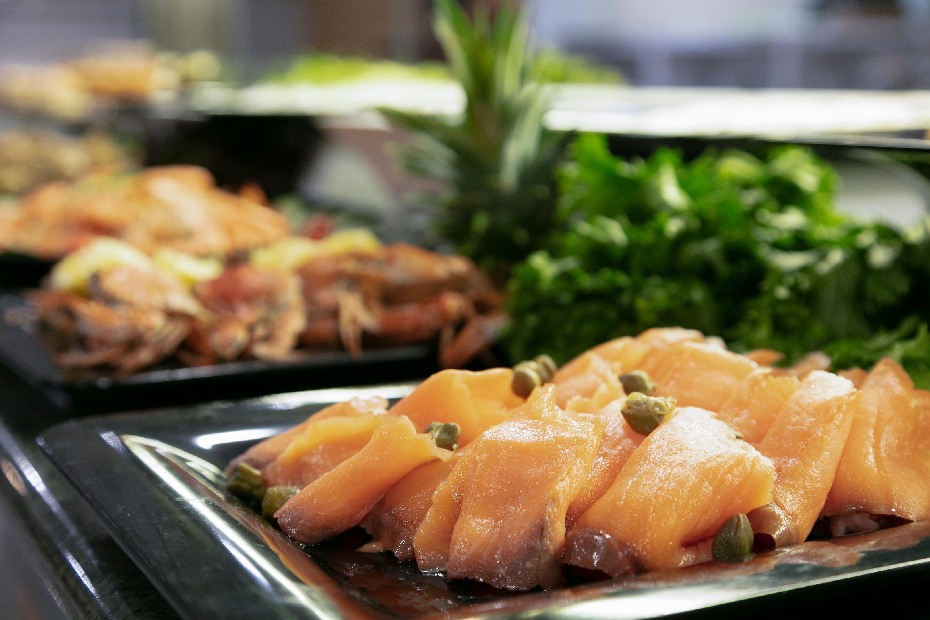 Un bufé con diversos platos, incluyendo salmón y verduras.
