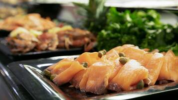 Un bufé con diversos platos, incluyendo salmón y verduras.