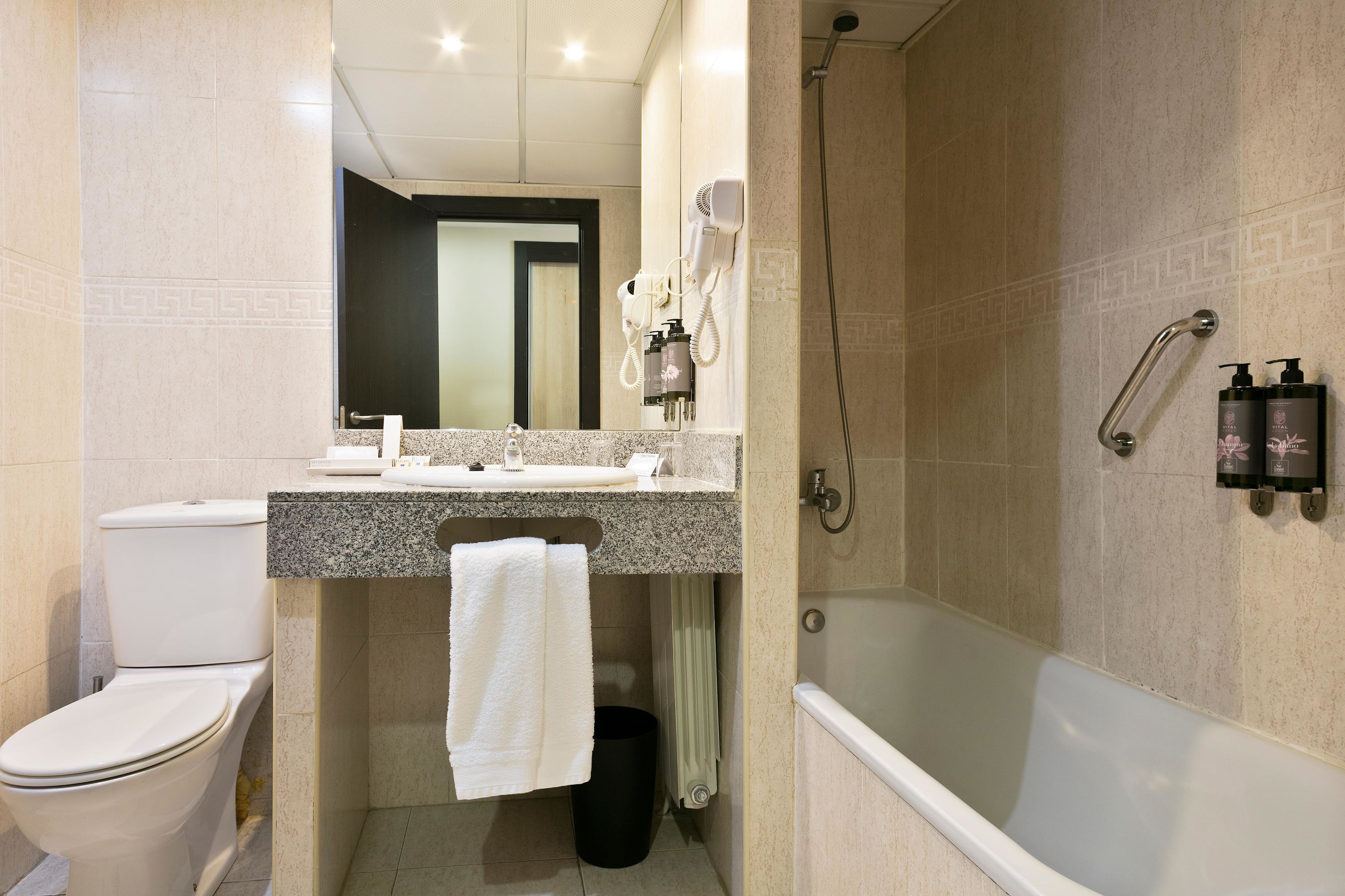 A modern bathroom with a toilet, sink, mirror, towel rack, shower, and bathtub.