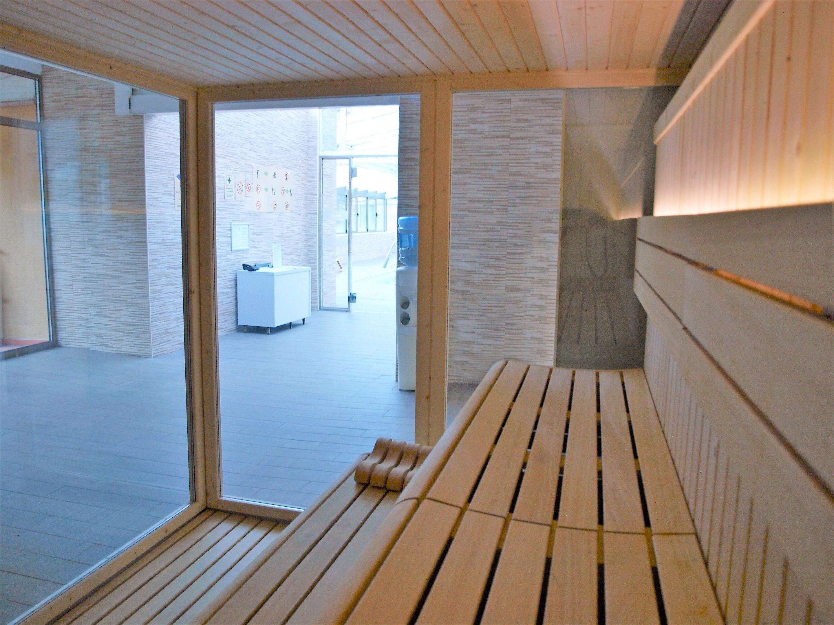 Ein modernes Interieur mit einer hölzernen Bank, einem Empfangstresen und Blick ins Freie.