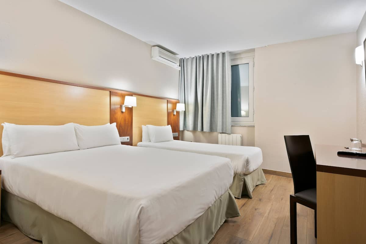 Habitación de hotel con dos camas, un escritorio y una silla.