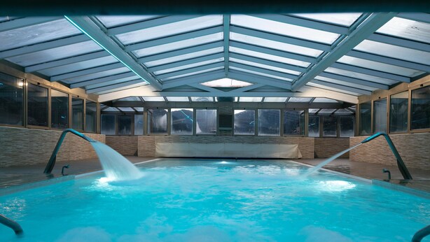 An indoor swimming pool with a glass ceiling, clear windows, and a bench along the wall. - Hotel Best Andorra Center (Andorra la Vella)