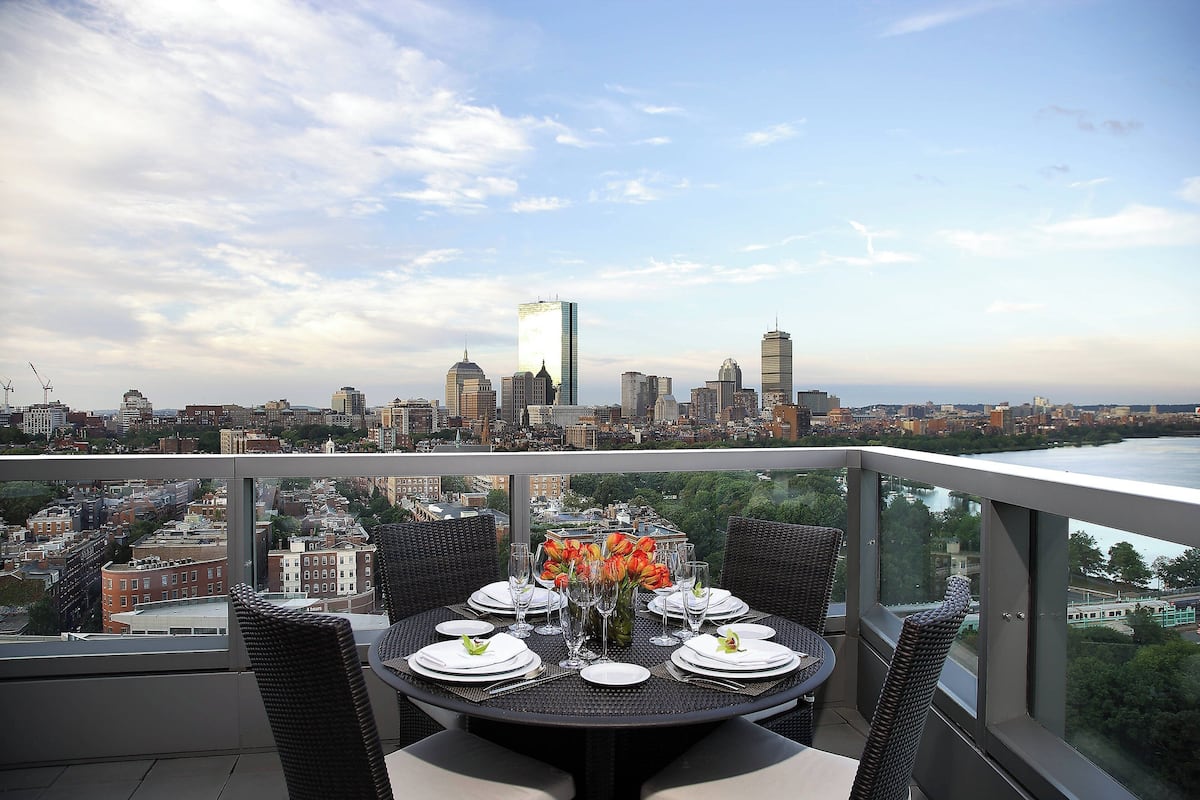 Mesa de comedor para seis personas con vistas a la ciudad, rodeada de sillas de mimbre.