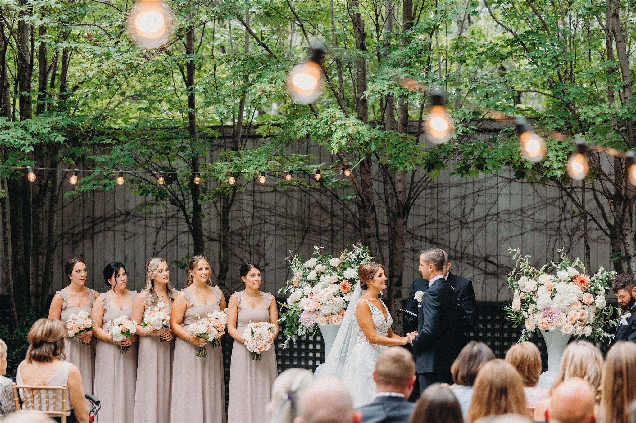 A wedding ceremony with a bride and groom, bridesmaids, and groomsmen.