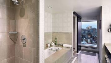 A modern bathroom with a shower, a bathtub, and a sink. There is a view of a cityscape through a large window.