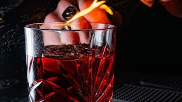 A clear glass with a red liquid, possibly a cocktail, on a dark surface.