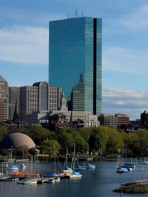 A cityscape with a prominent modern glass building, historic architecture, and a marina with boats.