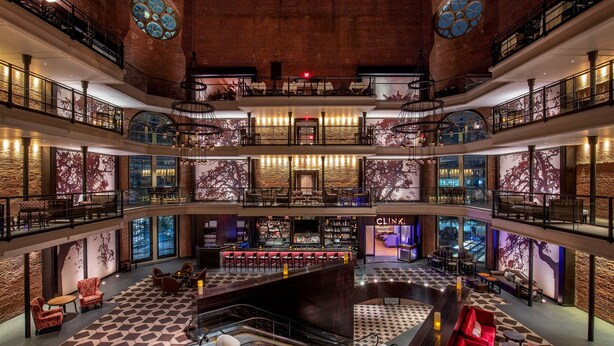 Un atrium à plusieurs niveaux comprenant un bar central, des espaces de détente et un escalier.