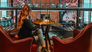 Un hall d’entrée spacieux avec un plafond haut, un grand lustre et un coin salon doté de fauteuils en cuir.