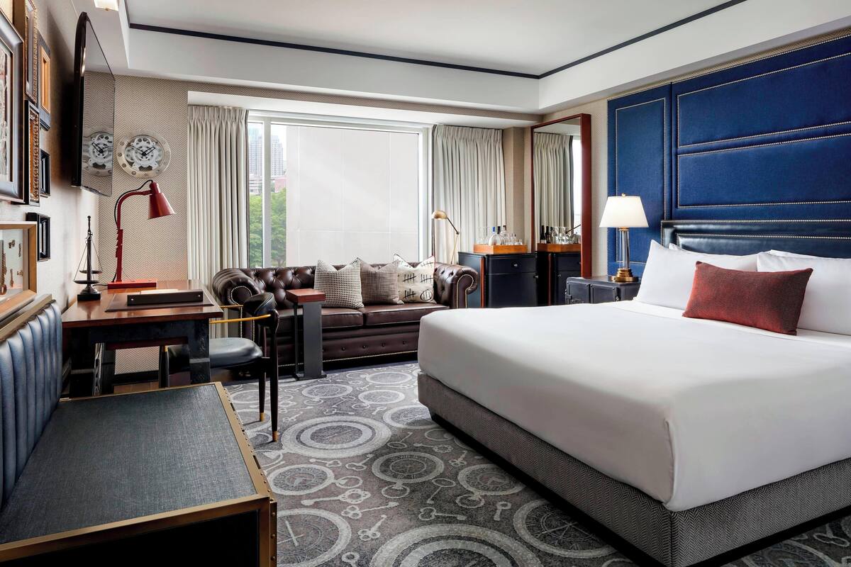 Un cuarto de hotel con una cama grande, un escritorio, un sofá y vistas al exterior.