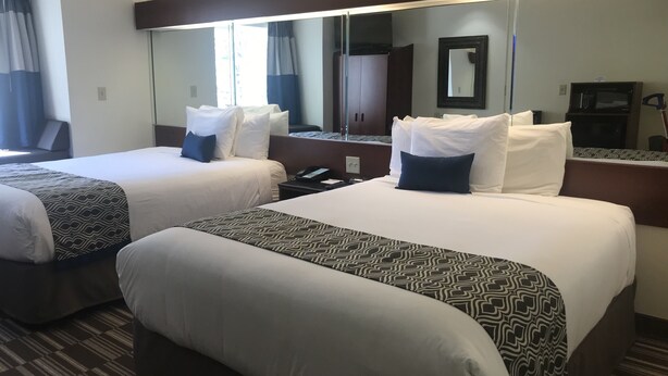 Habitación de hotel con dos camas, un espejo grande, un teléfono y un televisor.