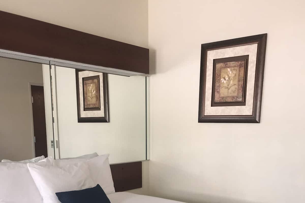 Una camera d'albergo con un letto grande, biancheria bianca, una coperta decorata e due quadri appesi al muro.