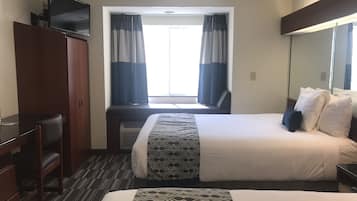 A hotel room with a bed, a desk, a chair, a wardrobe, and a television.