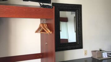 A hotel room with a bunk bed, a television, a mirror, a desk, and a chair.