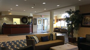 Un hall de hotel con mostrador de recepción, zona de estar y una planta grande.