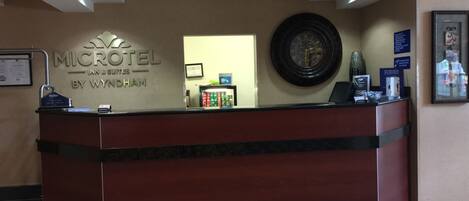 A reception desk with a clock, a framed picture, and a sign for the Microtel Inn & Suites by Wyndham.