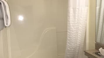 Un baño con ducha envuelta en vidrio, inodoro y toallero.