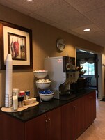Una zona de cocina con una cafetera, tazones de comida y un reloj en la pared.