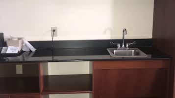 A compact kitchen with wooden cabinets, a black countertop, and a stainless steel sink.