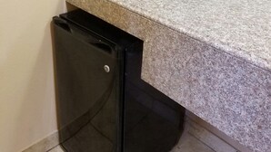 Eine Küchenzeile mit einer Mikrowelle, einem kleinen Kühlschrank und einer Kaffeemaschine auf der Arbeitsfläche.