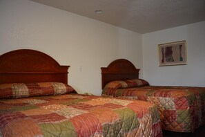 Two single beds with wooden headboards in a room with plain walls and a framed picture.