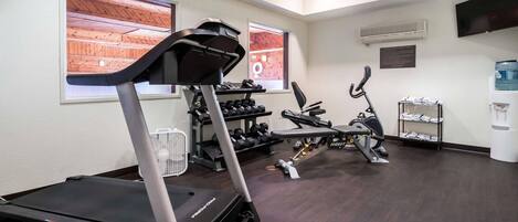 Une salle de sport équipée de tapis de course, d’haltères et d’autres appareils d’exercice.