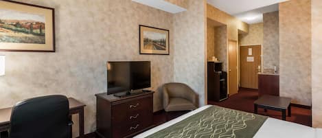 A hotel room with a bed, a desk, a chair, a television, and a dresser.