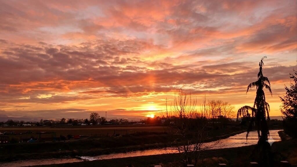 Un atardecer sobre un paisaje rural con una estatua en primer plano.
