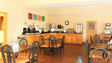 A restaurant with a counter, chairs, and tables.