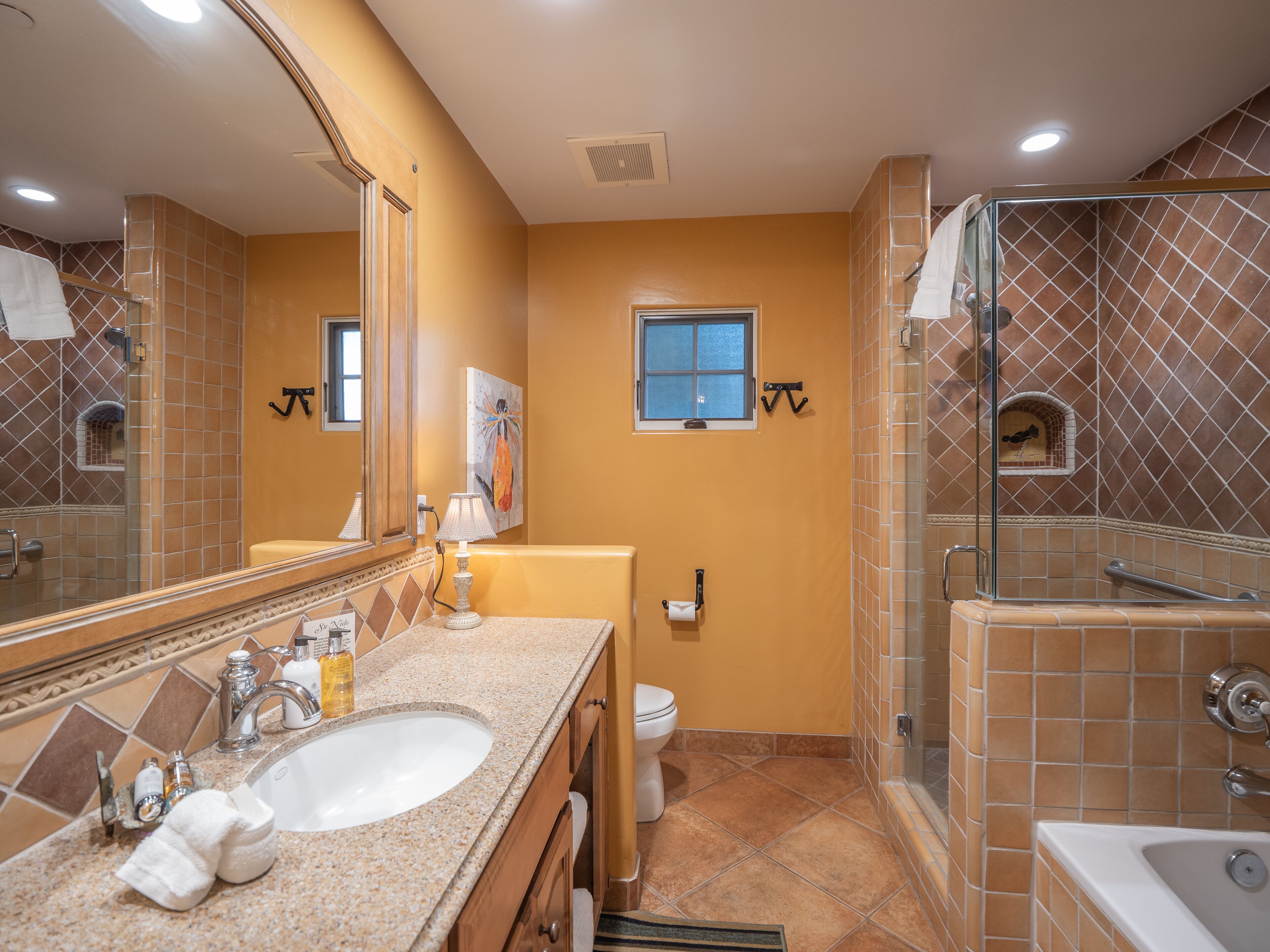 A bathroom with a large mirror, a sink, a toilet, and a shower area.
