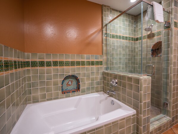 A bathroom with a bathtub, a glass shower enclosure, and a tiled wall with a decorative border.