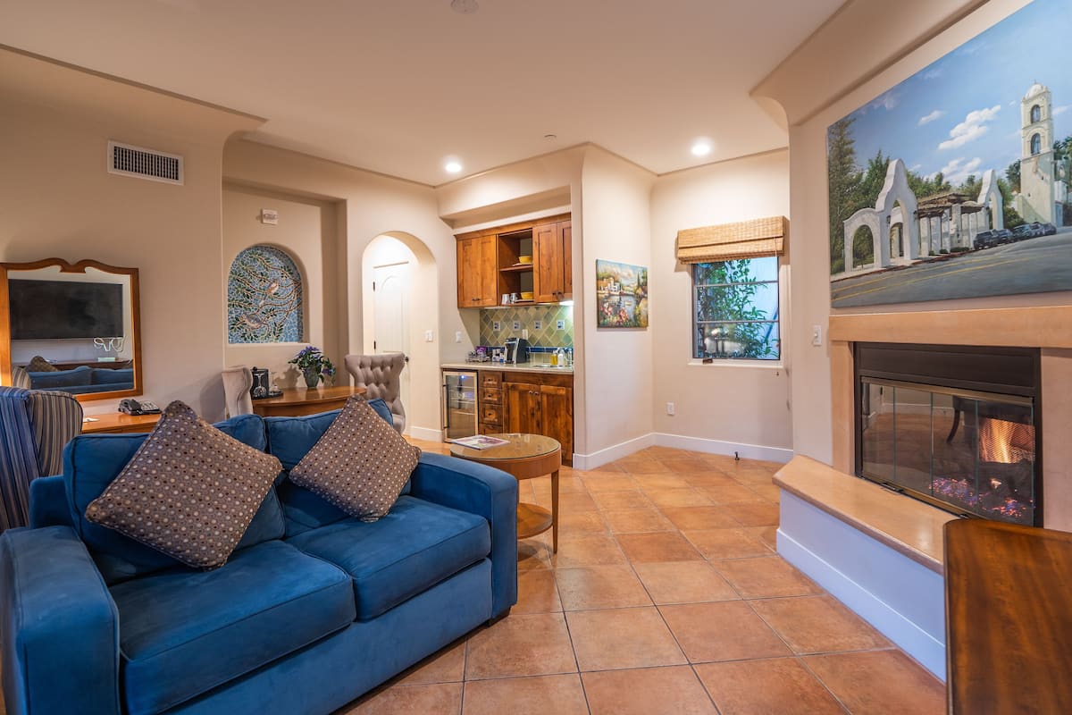 A living room with a blue sofa, a fireplace, and a kitchen in the background.