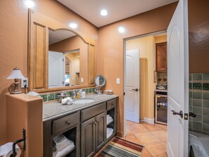 Une salle de bain équipée d’un lavabo, d’un miroir, d’un porte-serviettes et d’une porte donnant sur une autre pièce.