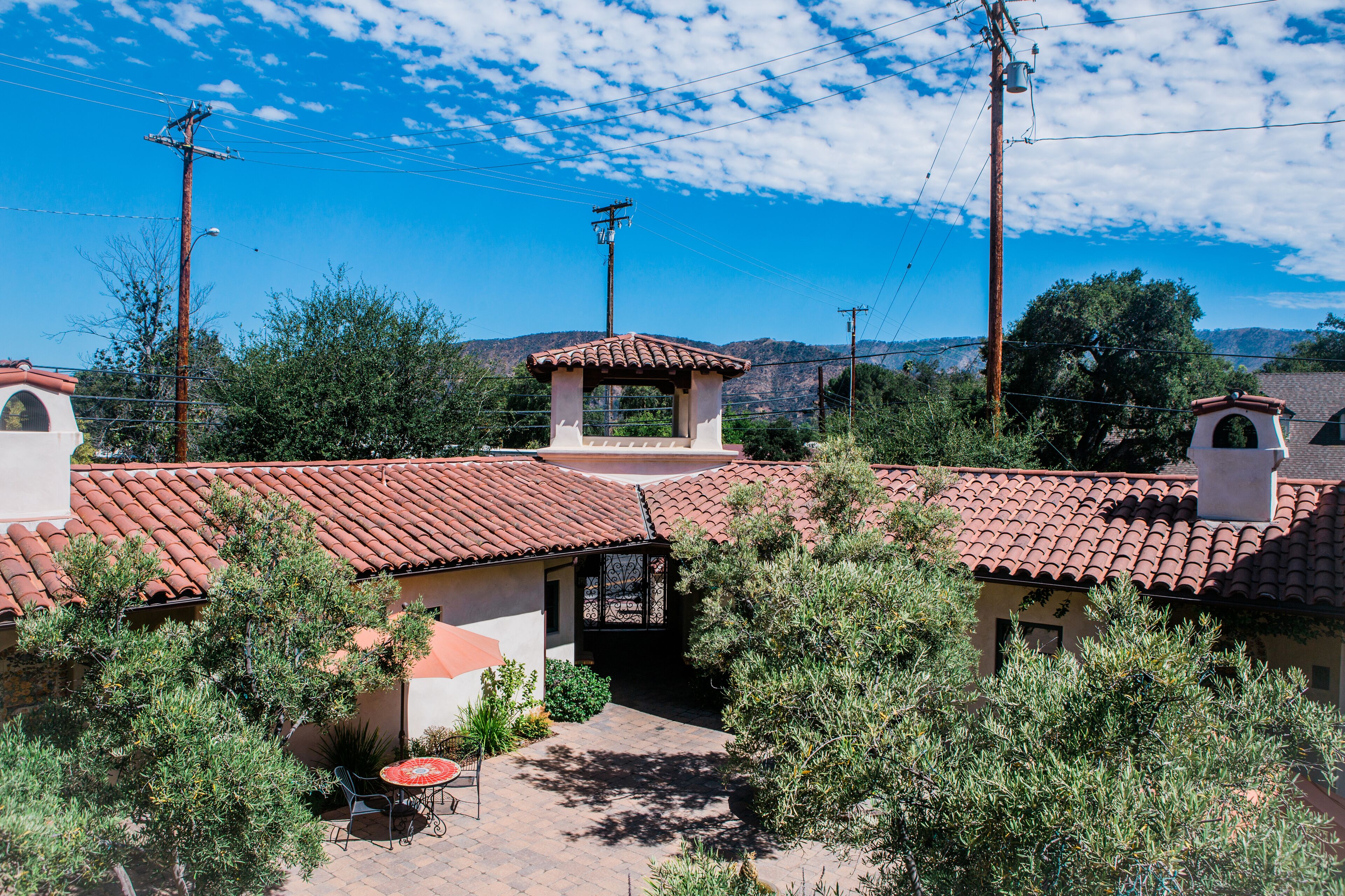 A courtyard with red-tiled roofs, surrounded by greenery and utility poles.