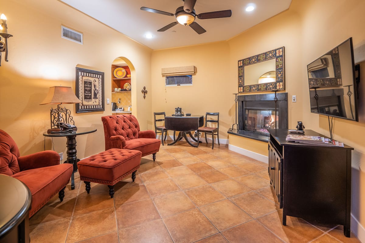 A living room with a fireplace, a dining table, and two red armchairs.