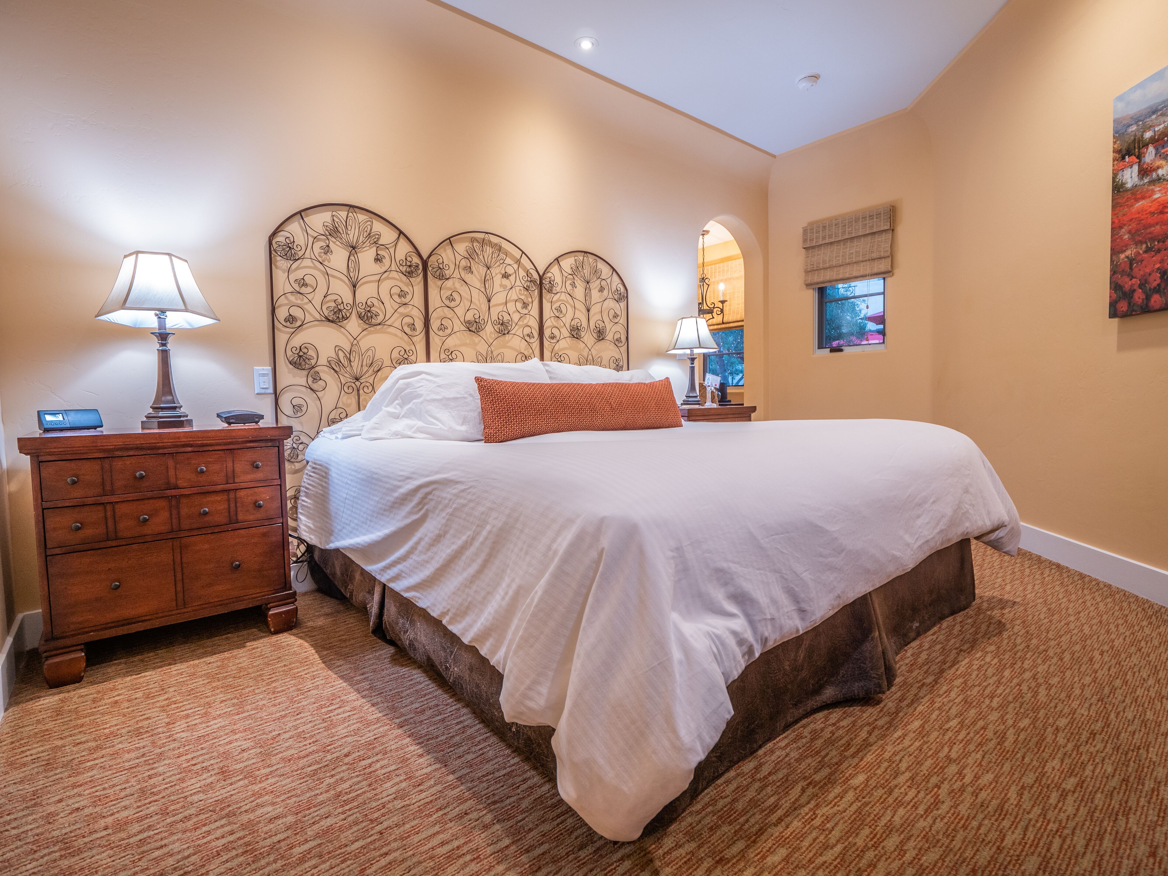 Un dormitorio con una cama grande, cómoda de madera y mesita de noche con lámpara.