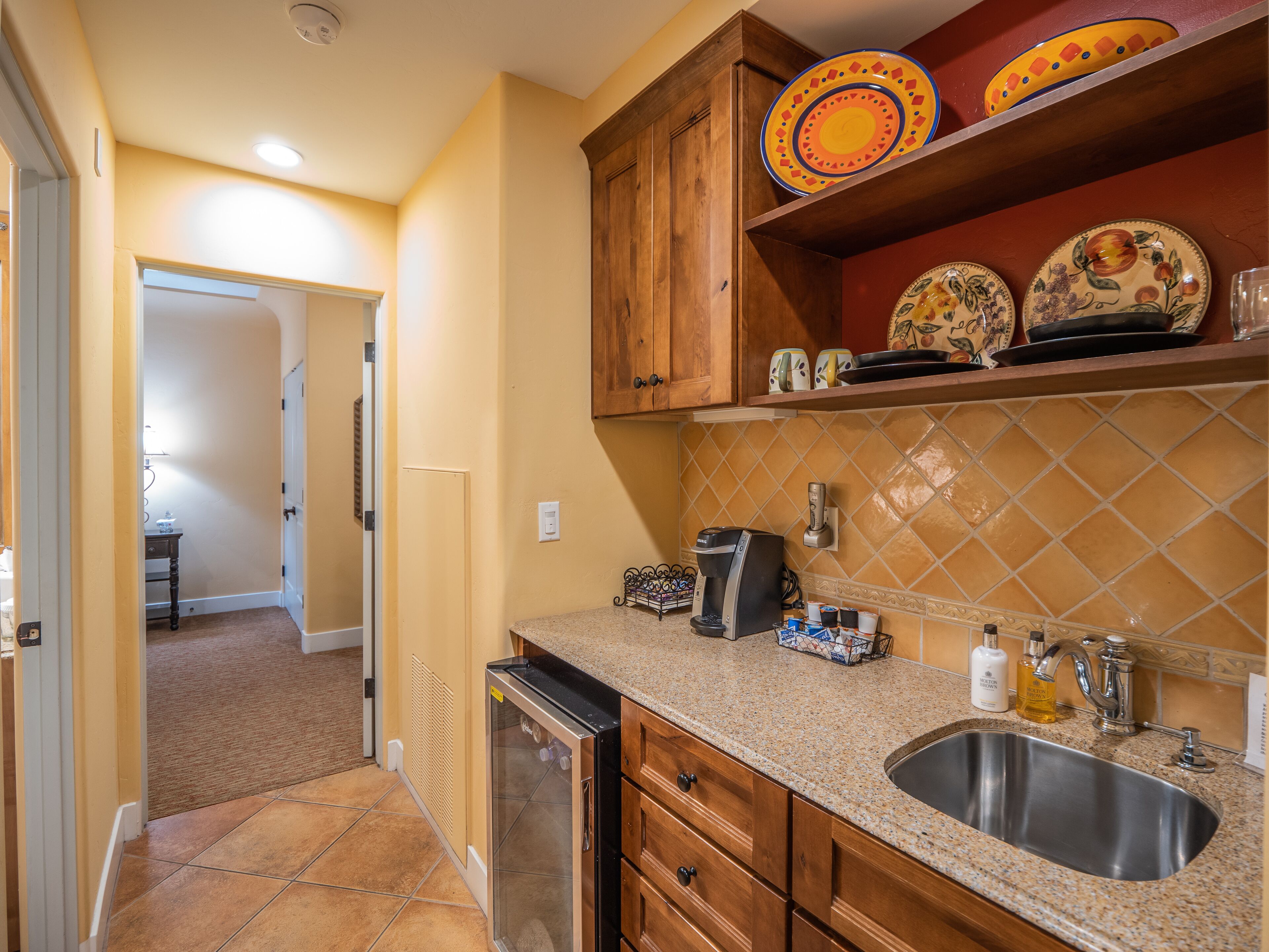 A kitchen with wooden cabinets, a granite countertop, a stainless steel sink, and a coffee maker.