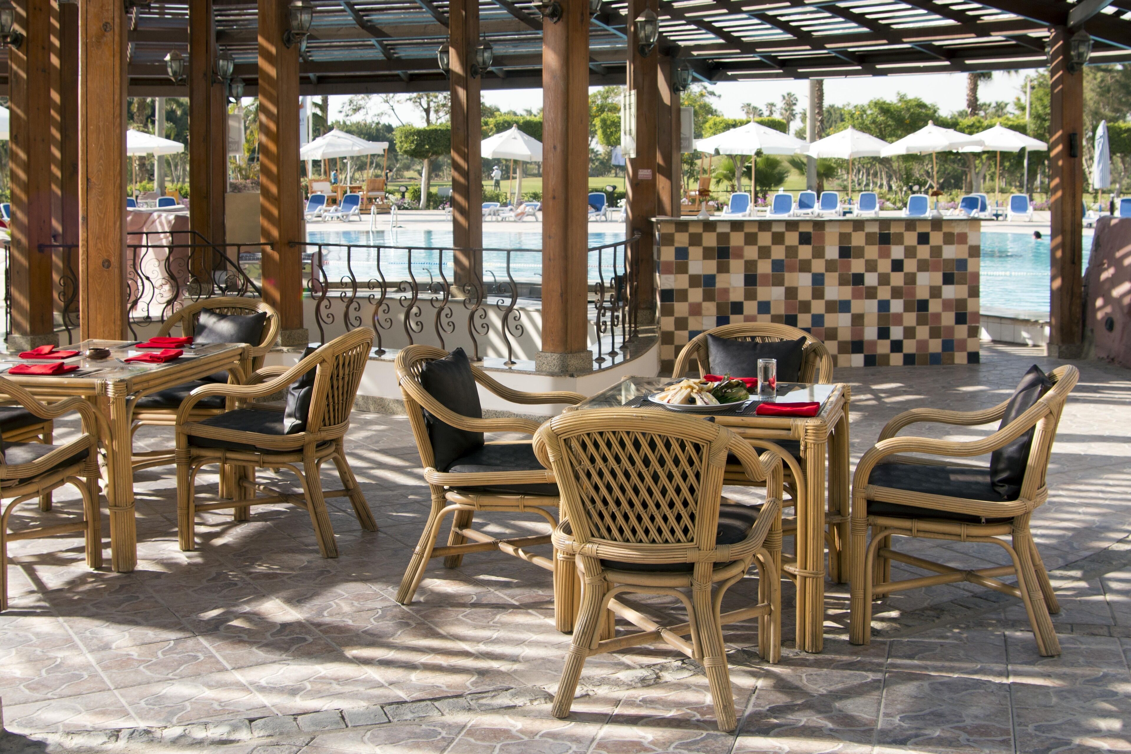 An outdoor seating area with wicker furniture and a checkered bar near a pool.